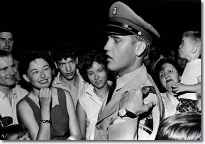 Elvis Presley explains the insignia on his uniform to fans at the gates of Graceland Sunday evening June 1, 1958. Elvis arrived late Saturday night for a two week leave. He was inducted into the army at Memphis March 24, 1958.