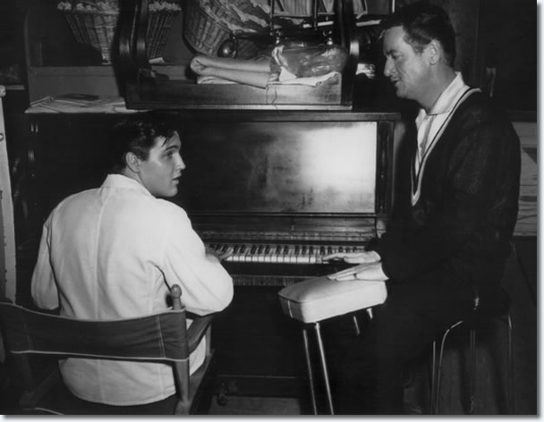 Elvis taking a break between takes is seated at a piano whilst talking to Charles O'Curran.