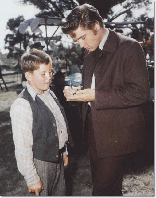 Elvis signs an autograph on the set of 'Love Me Tender'. From the book, Inside Love Me Tender