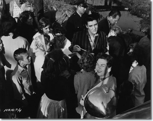 Elvis on location at Lake Pontchartrain Shack, New Orleans March 4,1958. Elvis signs some autographs for waiting fans. Elvis is wearing a shirt not seen in the movie, so he is either arriving or departing the location.