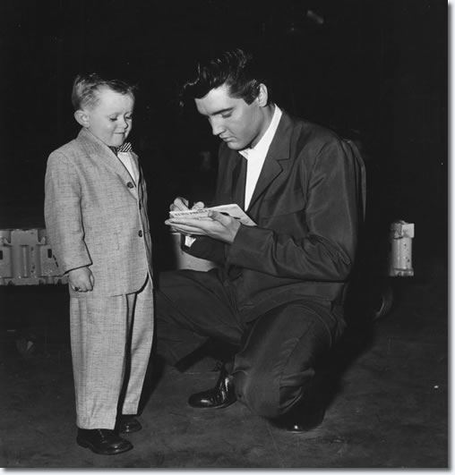 A young fan on the paramount set gets an autograph from Elvis,who is signing his name on the single release of Teddy Bear. Tuesday February 4, 1958.