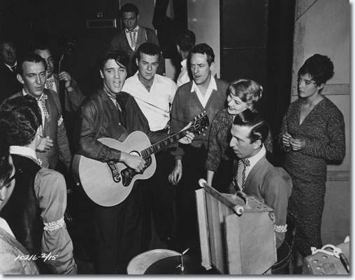 Hoyt Hawkins with (back to camera) takes part in a music number backstage with, Hugh Jarrett, Bill Black (holding upright bass), Elvis Presley, Scotty Moore at the top of picture, Ric Roman next to Elvis, Charles O'Curren, Patti Page, D.J. Fontana sat with his drum kit, and Liliane Montevecchi (Nina).
