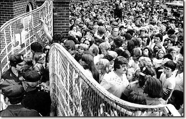 A crowd pushes toward the gates of Graceland Mansion in Memphis, to view the body of Elvis Presley