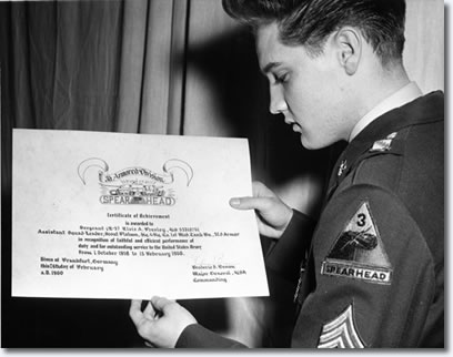 Elvis Presley holding the certificate of achievement that the Army presented to him upon his honorable discharge in February of 1960.